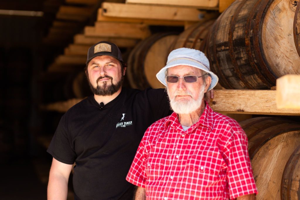 Royce Neeley and Papaw stand in the rick house at Neeley Family Distillery.